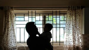 Vater hält sein Kind am Abend in der Küche, Silhouette vor dem Fenster