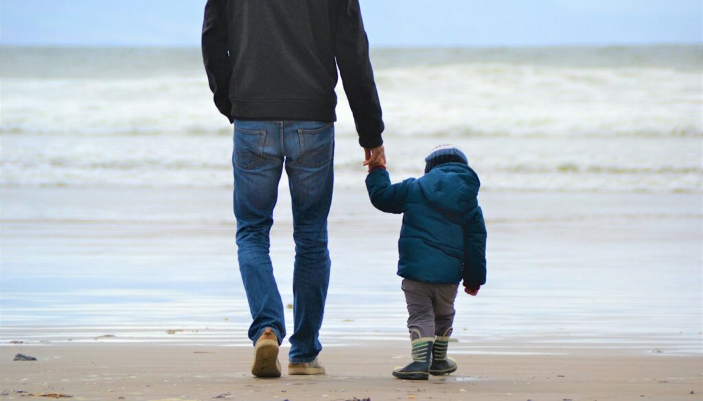 Vater und Sohn gehen nebeneinander am Meeresufer