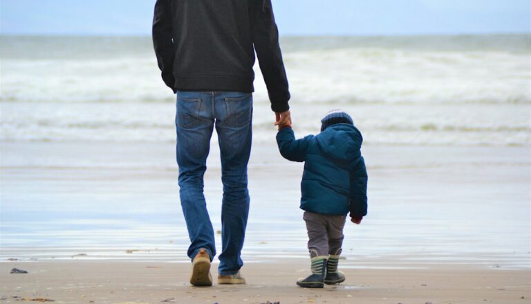 Vater und Sohn gehen nebeneinander am Meeresufer